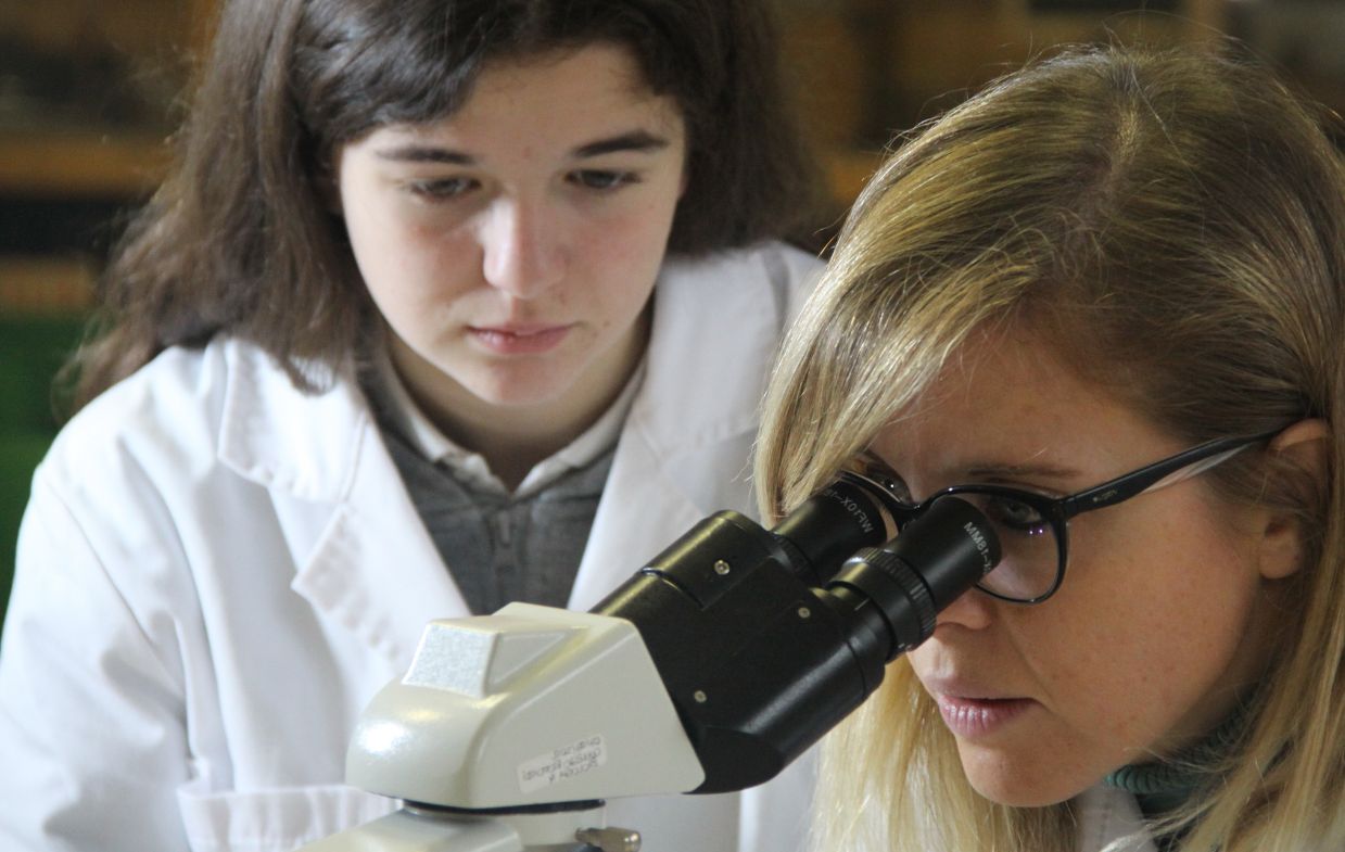 Science teacher, showing the students how to use the microscope.